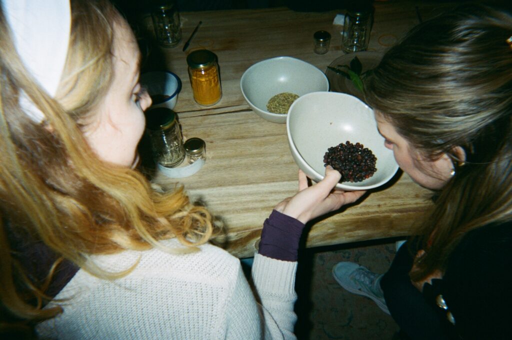 Two women are smelling ingredients from a bowl.